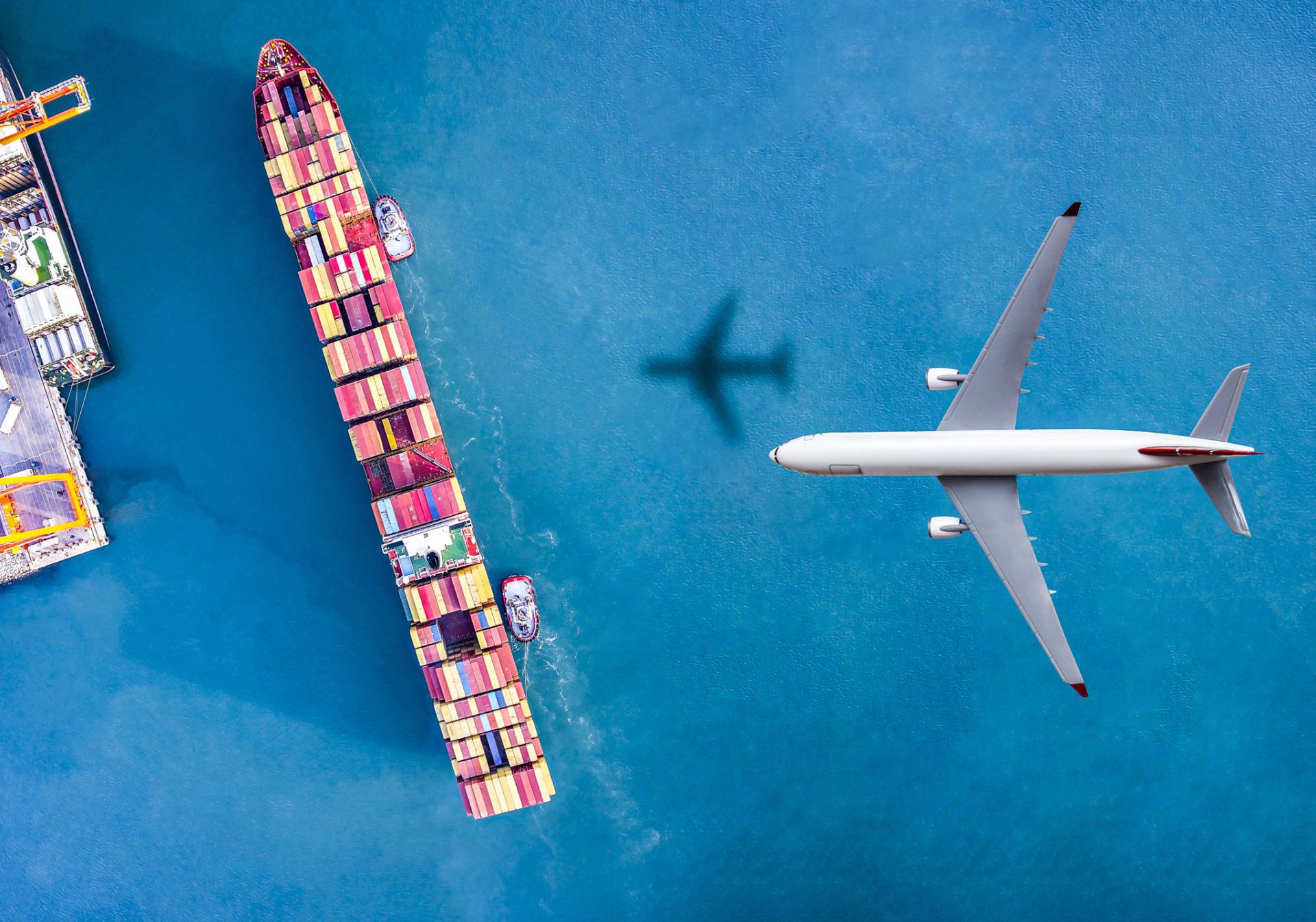 Airplane flying above cargo ship.